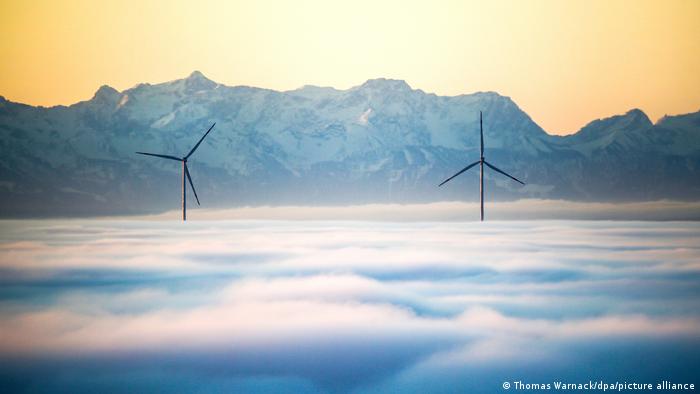 Vetrenjače izranjaju kroz jutarnju maglu u Utenvajleru na jugu Nemačke. Dobar objektiv i povoljno vreme čine čuda: Alpi deluju kao da su nadomak ruke, a u stvari su stotinu kilometara udaljeni.