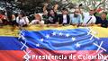 Venezolanos y colombianos celebran la apertura de la frontera común sobre una valla con banderas.