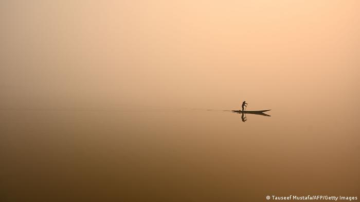 Čovek vesla u čamcu na jezeru Dal u Srinagaru u Indiji. Magla je izbrisala razliku između neba i vode.