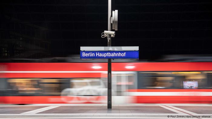Berlin Hauptbahnhof steht auf dem Schild auf einem Bahnsteig im Hauptbahnhof Berlin, während ein Zug einfährt.