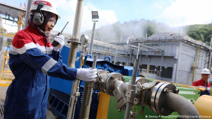 Eine Ingenieurin steht in Schutzkleidung an der Geothermal Power Plant in Indonesien