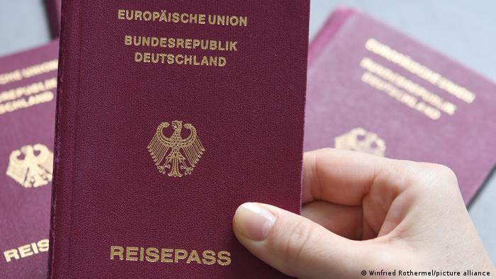 eine Hand hält einen Reisepass der Bundesrepublik Deutschland hoch