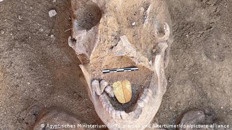 Ein Schädel mit einer goldenen, zungenförmigen Platte im Mund.