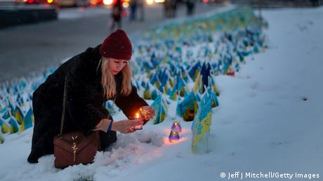 Jedna z mieszkanek Kijowa zapala świeczkę w intencji ofiar wojny.
