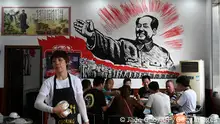 TOPSHOT - This photo taken on May 26, 2021 shows people eating in front of an image of late Chinese communist leader Mao Zedong at a restaurant in Shaoshan, in China's central Hunan province. - As the Chinese Communist Party prepares to mark its 100th anniversary, a nationwide propaganda campaign has gone into overdrive, aiming to shore up the legitimacy of the party and its President Xi Jinping. - To go with AFP story China-politics-party-anniversary, ADVANCER by Laurie Chen (Photo by Jade GAO / AFP) / To go with AFP story China-politics-party-anniversary, ADVANCER by Laurie Chen (Photo by JADE GAO/AFP via Getty Images)