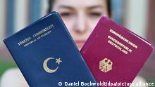Foto simbolike: Një grua duke mbajtur në dorë dy pasaporta: turken dhe gjermanen. 