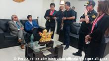 In this photo provided by Peru's police administration office, former President Pedro Castillo, second from left, and former Prime Minister Anibal Torres, far left, sit as prosecutor Marco Huaman stands at center inside a police station, where Castillo and Torres' status was not immediately clear, in Lima, Peru, Wednesday, Dec. 7, 2022. Peru’s Congress removed Castillo from office Wednesday and replaced him with the vice president, shortly after the president decreed the dissolution of the legislature ahead of a scheduled vote to oust him. (Peru's police administration office via AP)