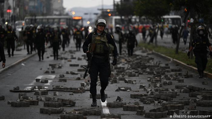 Fuerzas de seguridad peruanas en una calle destrozada tras enfrentamientos con seguirdores de Castillo. 