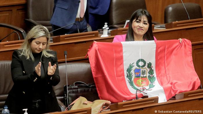 Un miembro del Congreso peruano sostiene una bandera del país sudamericano tras la destitución de Castillo. 