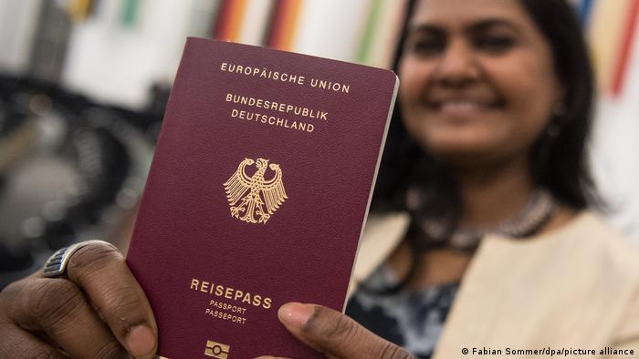 Frau hält deutschen Reisepass in die Kamera