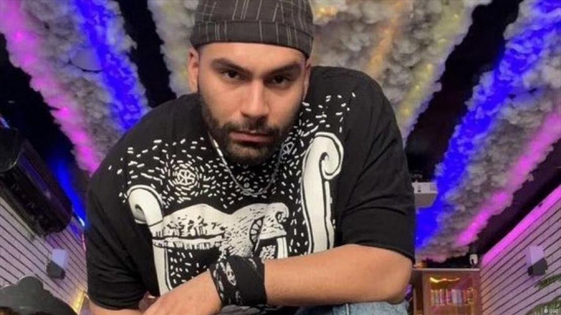 Mohsen Shekari, posing for the camera in a beanie hat against a brightly coloured background