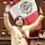 Peru I Dina Boluarte com a faixa presidencial e os braços erguidos