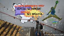 A man walks past a graffiti reading First rule of Kherson’s club: Kherson is Ukraine! Always, without options in central Kherson on December 8, 2022, amid the Russian invasion of Ukraine. - Few weeks after Russians left the city, a group of Ukrainian artists painted encouraging pro-Ukrainian graffities in central Kherson to celebrate its liberation. (Photo by Genya SAVILOV / AFP)