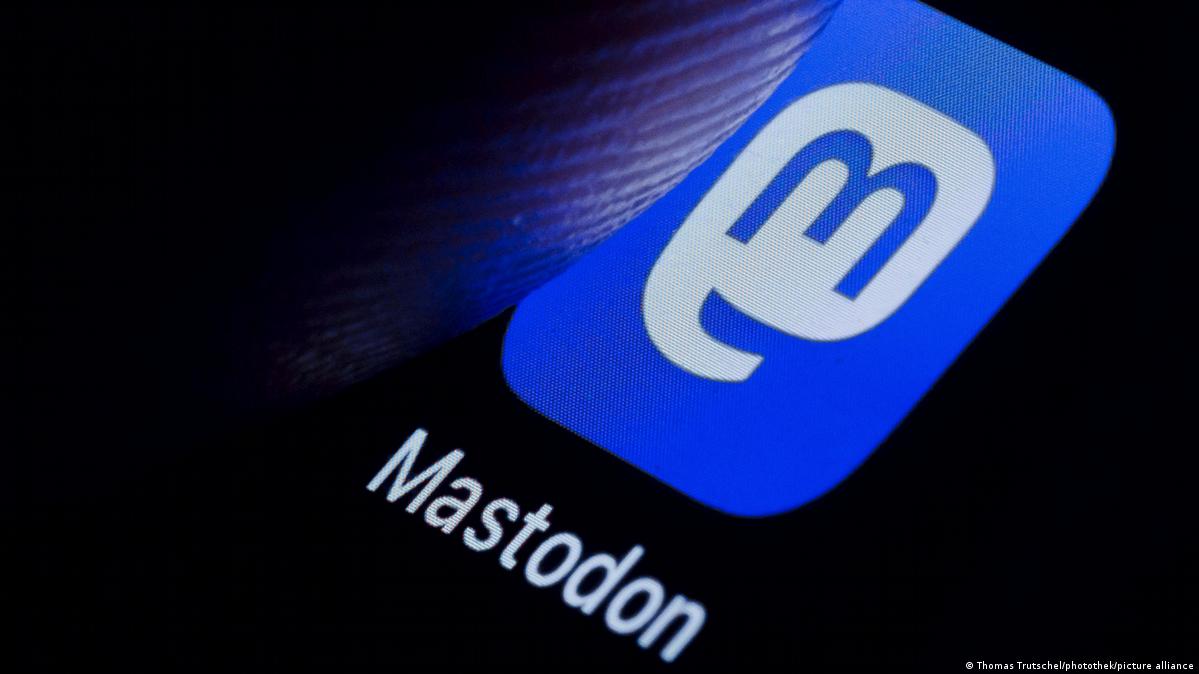 A finger taps the Mastodon logo on a smartphone screen