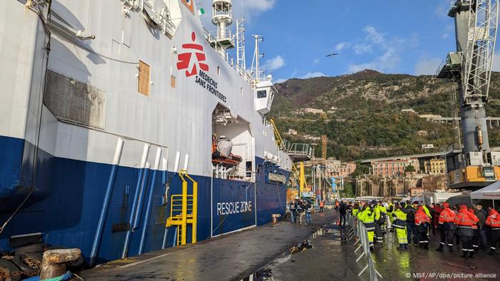 Am Hafen von Salerno erhebt sich die Bordwand des Rettungsschiffs Geo Barents , hinter den Absperrungen stehen Arbeiter in bunter Schutzkleidung