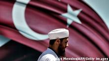 An imam passes the Turkish flag during a demonstration in support of Turkey's President Erdogan (not pictured) at the Sarachane park in Istanbul on July 19, 2016. Turkey has demanded the resignation of 1,577 university deans suspected of being connected with Friday's attempted coup, state-run news agency Anadolu reported July 19. The country's higher education board made the demand for deans at state and private foundation universities to resign, Anadolu said.
/ AFP / ARIS MESSINIS (Photo credit should read ARIS MESSINIS/AFP via Getty Images)