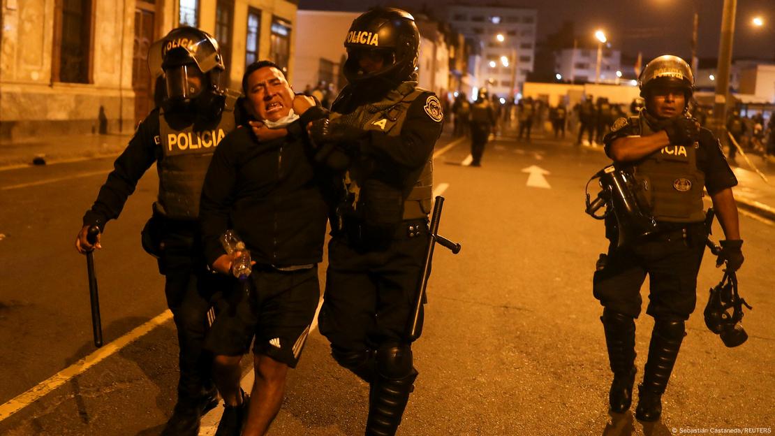 Police in riot gear arrest a protester in Lima, Peru