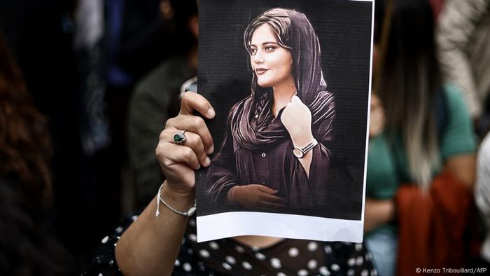 Mujer en una protesta porta un retrato de Mahsa Amini.