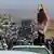 A woman stands atop a car in front in Iran