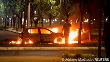 A person stands next to a burning vehicle as supporters of Brazil's President Jair Bolsonaro protest after supreme court justice Alexandre de Moraes ordered a temporary arrest warrant of indigenous leader Jose Acacio Serere Xavante for alleged anti-democratic acts, in Brasilia, Brazil, December 12, 2022. REUTERS/Adriano Machado