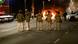 Militares fazem fila de costas, enquanto observam fogo em veículo Militares fazem fila de costas, enquanto observam fogo em veículo