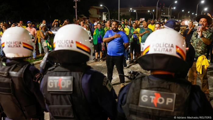 Foto de manifestantes que protestan frente a agentes de la Policía Militar.