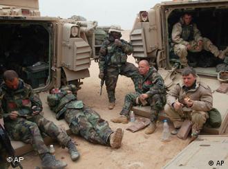 Chris Tomlinson, right, of the Associated Press, eats a meal ready to eat, or MRE, at a temporary camp in the desert with U.S. Army soldiers from the A Company 3rd Battalion, 7th Infantry Regiment about 100 miles south of Baghdad March 24, 2003. Tomlinson was among journalists embedded with the troops during the war in Iraq. (AP Photo/John Moore)