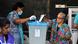 Two women dropping ballots in a plastic container Two women dropping ballots in a plastic container