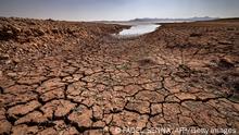 A picture shows cracked earth at al-Massira dam in Ouled Essi Masseoud village, some 140 kilometres (85 miles) south from Morocco's economic capital Casablanca, on August 8, 2022 amidst the country's worst drought in at least four decades. - Residents of Morocco's Ouled Essi Masseoud village are suffering from a series of successive droughts, prompting them to rely solely on sporadic supplies in public fountains and from private wells. The situation is critical, given the village's position in the agricultural province of Settat, near the Oum Errabia river and al-Massira dam, Morocco's second largest. Its reservoir supplies drinking water to several cities, including the three million people who live in Casablanca. But latest official figures show it is now filling at a rate of just five percent. (Photo by FADEL SENNA / AFP) (Photo by FADEL SENNA/AFP via Getty Images)