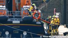 Rescue workers handle what appears to be a body bag onto a stretcher, as they return to the Port of Dover amid a rescue operation of a missing migrant boat, in Dover, Britain December 14, 2022. REUTERS/Peter Nicholls