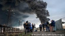 Journalists and residents stand as smoke rises after an attack by Russian army in Odessa, on April 3, 2022. - Air strikes rocked Ukraine's strategic Black Sea port Odessa early Sunday morning, according to an interior ministry official, after Kyiv had warned that Russia was trying to consolidate its troops in the south. (Photo by BULENT KILIC / AFP) (Photo by BULENT KILIC/AFP via Getty Images)
