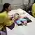 Mujer japonesa en el médico con su bebé tendido en una camilla y personal sanitario alrededor.