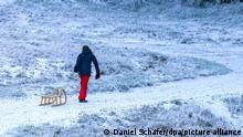 Eine junge Frau zieht einen Schlitten einen Berg hinauf. Im Erzgebirge gingen zwei bis drei Zentimeter Neuschnee nieder. +++ dpa-Bildfunk +++