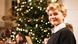 Ein Junge mit blondem Haar lächelt in die Kamera. Im Hintergrund steht ein leuchtender Weihnachtsbaum. Ein Junge mit blondem Haar lächelt in die Kamera. Im Hintergrund steht ein leuchtender Weihnachtsbaum.