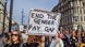 A protester holds up a sign saying "End the gender pay gap" A protester holds up a sign saying "End the gender pay gap"