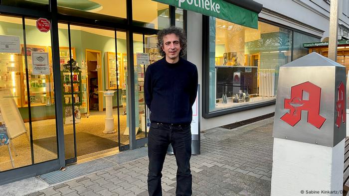Kranich-Apotheke in Berlin-Charlottenburg. Fatih Kaynak steht vor seiner Apotheke und hat die Hände hinter dem Rücken verschränkt. 