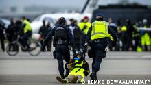 The Marechaussee arrest a protester as Milieudefensie, Extinction Rebellion, Greenpeace and other organisations members sit in front of an aircraft during a protest 'SOS for the climate' at Schiphol Airport, near Amsterdam on November 5, 2022. (Photo by Remko de Waal / ANP / AFP) / Netherlands OUT