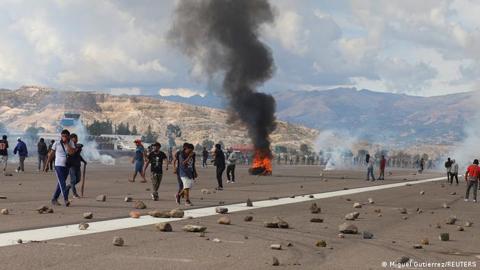 Demonstranten zwischen brennenden Reifen und Steinen auf dem Rollfeld des Flughafens von Ayacucho
