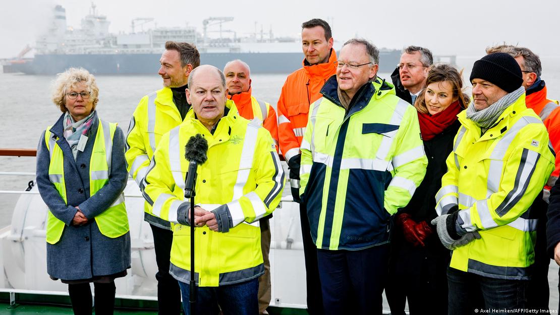 Chancellor Scholz (in front of a microphone) und Robert Habeck (right) are seen inaugurating a new LNG terminal in December 2022