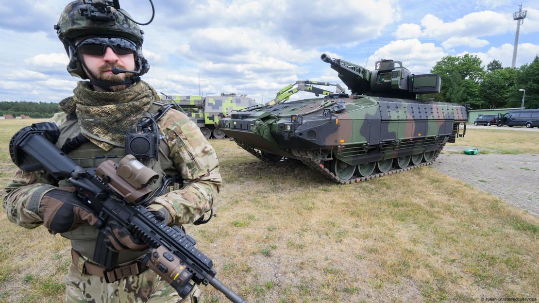 Soldado armado em frente a um tanque Puma