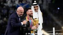 Argentina's Lionel Messi receives the trophy from FIFA President Gianni Infantino, left, and the Emir of Qatar Sheikh Tamim bin Hamad Al Thani, after winning the World Cup final soccer match between Argentina and France at the Lusail Stadium in Lusail, Qatar, Sunday, Dec. 18, 2022. Argentina won 4-2 in a penalty shootout after the match ended tied 3-3. (AP Photo/Martin Meissner)