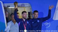 20.12.2022+++ Argentina's Lionel Messi holds the FIFA World Cup trophy as he deplanes, with coach Lionel Scaloni, in Buenos Aires, Argentina, Tuesday, Dec. 20, 2022. (AP Photo/Gustavo Garello)