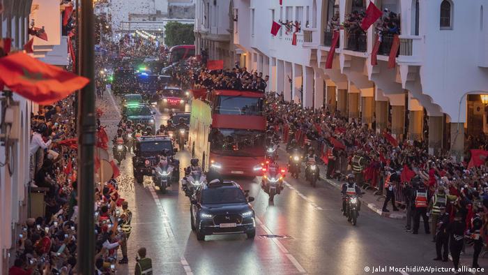 مشجعون يهتفون خلال مرور موكب المنتخب المغربي لكرة القدم من أحد الشوارع في وسط الرباط