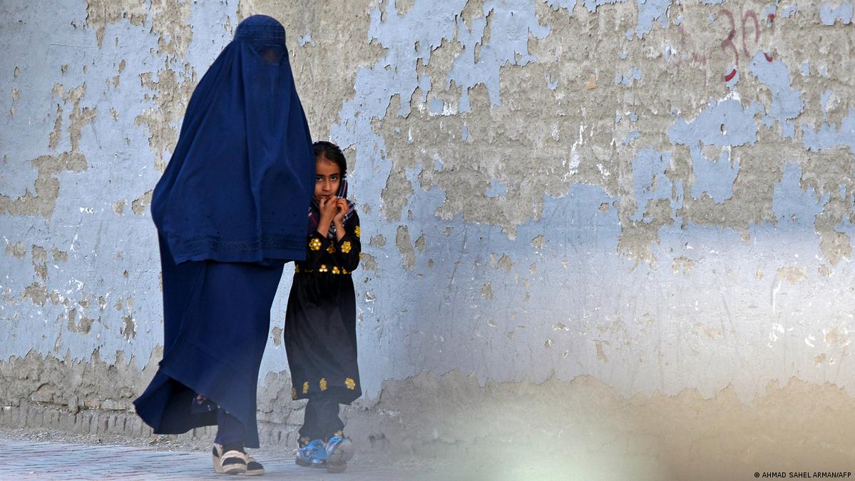 A burqa-clad woman walks with a girl along a street in Kabul on May 7, 2022
