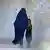 Una mujer con burka, acompañada de una niña.