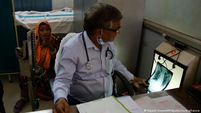 Un médico revisa un examen de una paciente con síntomas de tuberculosis.