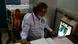An Indian doctor looks at a lung X-ray with female patient behind him An Indian doctor looks at a lung X-ray with female patient behind him