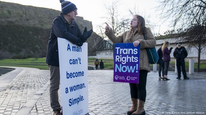 Ein Mann und eine Frau stehen mit Protestschildern in der Nähe des Edinburgher Parlaments