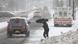 Pessoa atravessa uma rua, com guarda-chuva. Há muita neve acumulada. Pessoa atravessa uma rua, com guarda-chuva. Há muita neve acumulada.