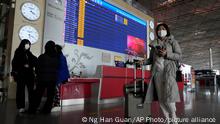 Passengers pass near a flight departure board in a Capital airport terminal in Beijing, Tuesday, Dec. 13, 2022. Some Chinese universities say they will allow students to finish the semester from home in hopes of reducing the potential of a bigger COVID-19 outbreak during the January Lunar New Year travel rush. (AP Photo/Ng Han Guan)